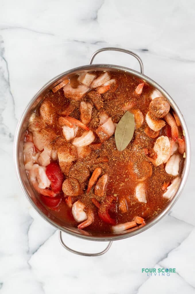 Topview photo of ingredients to make Keto Gumbo in a stock pot, ready to cook, including veggies, meat, and spices.