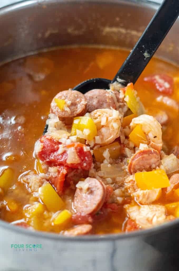 Closeup photo of Keto Gumbo in a stock pot. There is a ladle scooping up Gumbo, ready to serve.