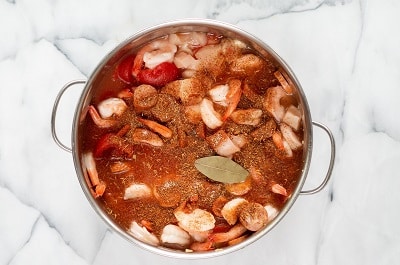 Topview photo of ingredients to make Keto Gumbo in a stock pot, ready to cook, including veggies, meat, and spices.