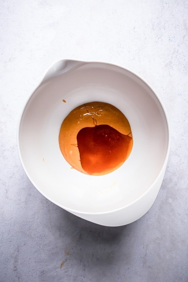 top view photo of nut butter and maple syrup in a white bowl, ready to be mixed together