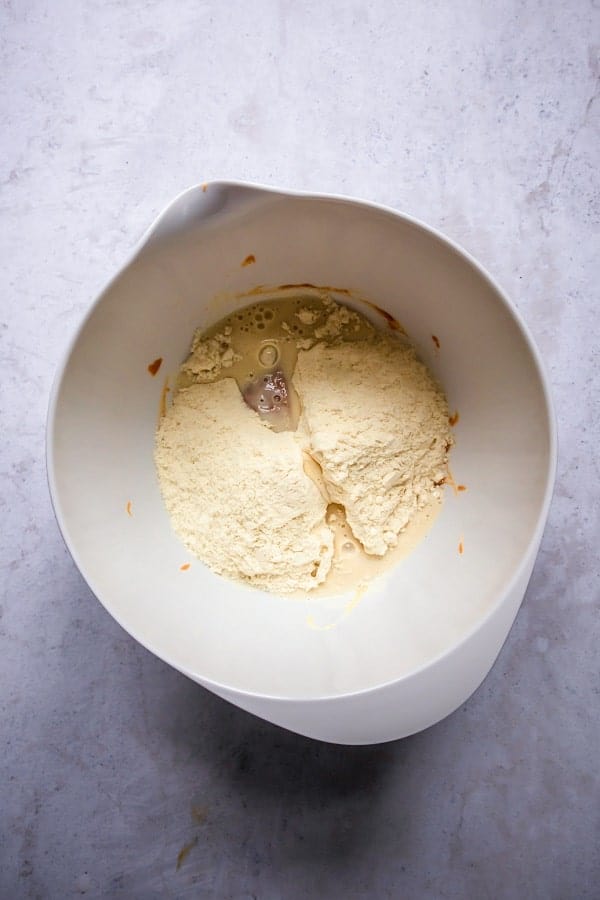 top view photo of protein powder and dairy free milk in a white bowl with nut butter and maple syrup mixture, ready to be mixed.