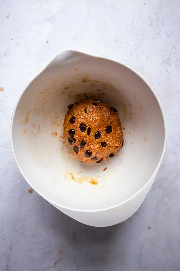top view photo of dough for protein cookie dough, in a white bowl, mixed into a large ball