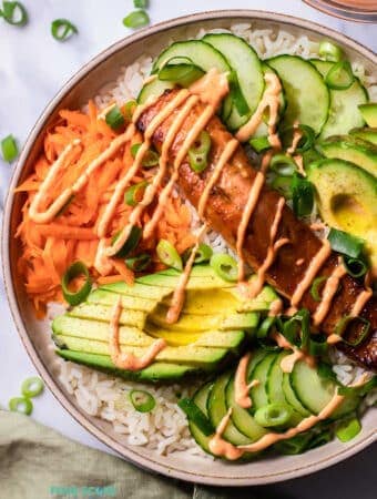 Top view photo of Salmon Rice Bowl, in a bowl and ready to serve. There is a kitchen towel next to the bowl.