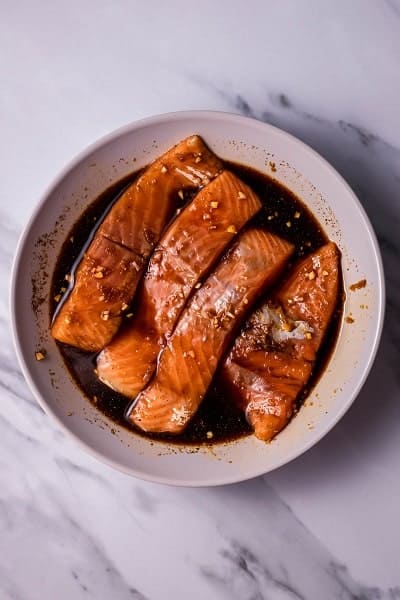 Top view photo of salmon soaking in a bowl of marinade to make Salmon Rice Bowls.