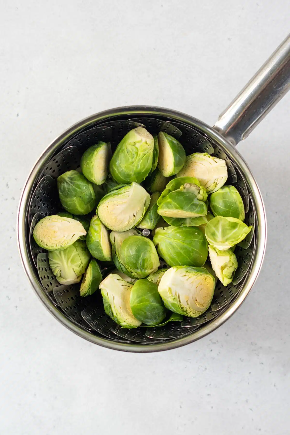 top view photo of brussels sprouts in a vegetable steamer inside a saucepan