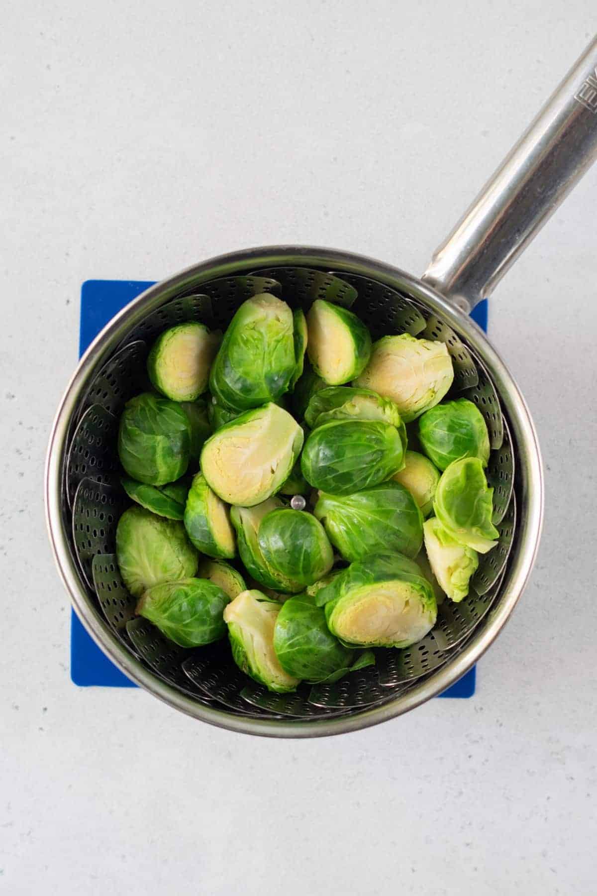 top view photo of brussels sprouts in a vegetable steamer inside a saucepan on top of a hot plate