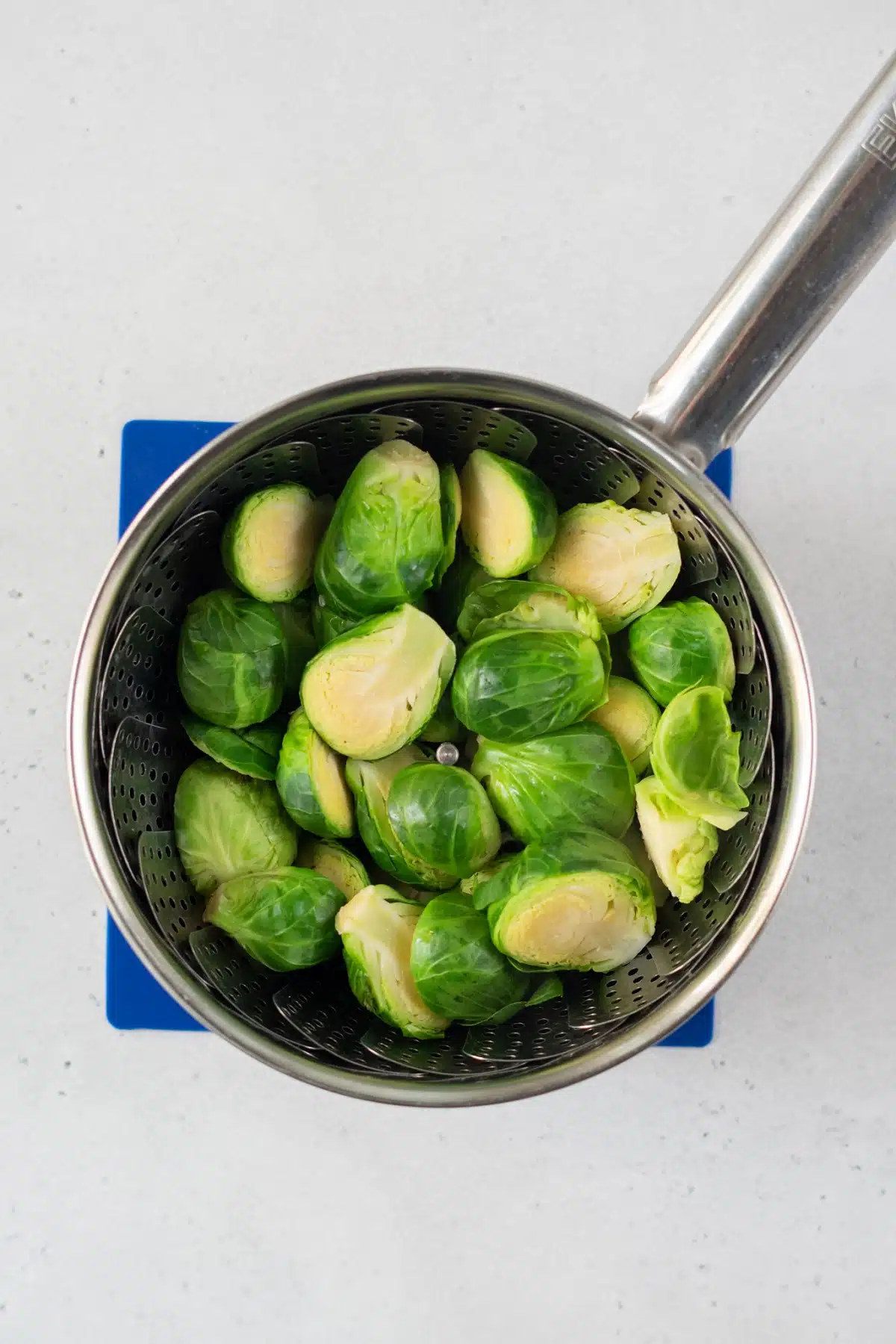 top view photo of brussels sprouts in a vegetable steamer inside a saucepan on top of a hot plate