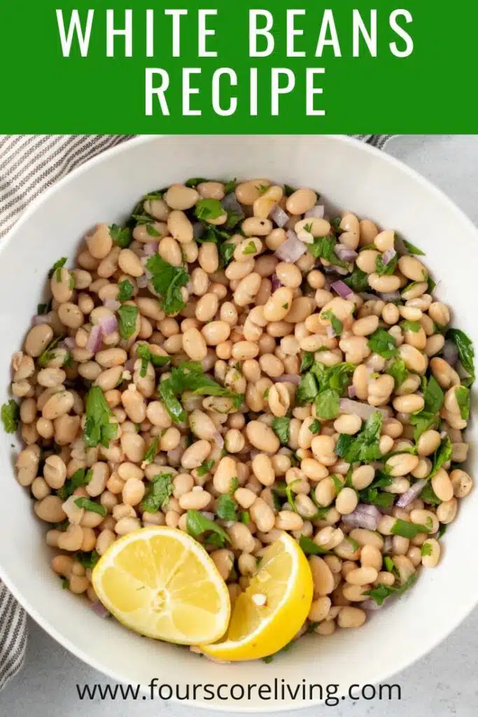 pinterest image of white beans recipe in a white bowl with lemon wedges on top of the white beans
