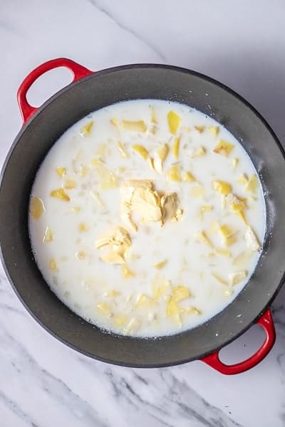 Top view photo of butter, milk, potatoes, and onions in a large stockpot.