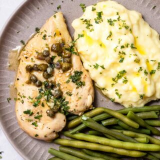 Top view photo of Chicken Paillard, on a plate with green beans and mashed potatoes.