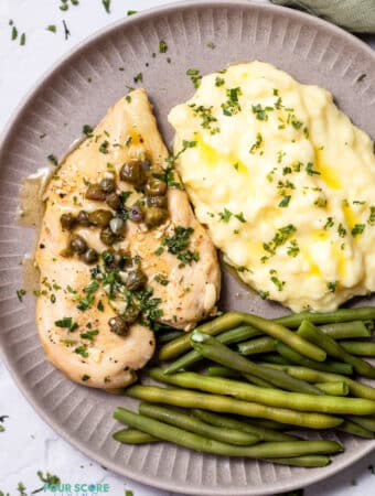 Top view photo of Chicken Paillard, on a plate with green beans and mashed potatoes.