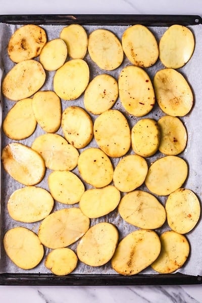 Top view photo of potato slices on a baking sheet, ready to bake.