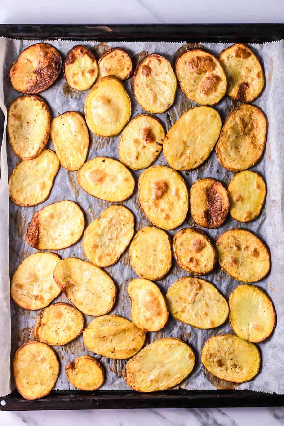 Top view photo of cooked potato slices on a baking sheet.
