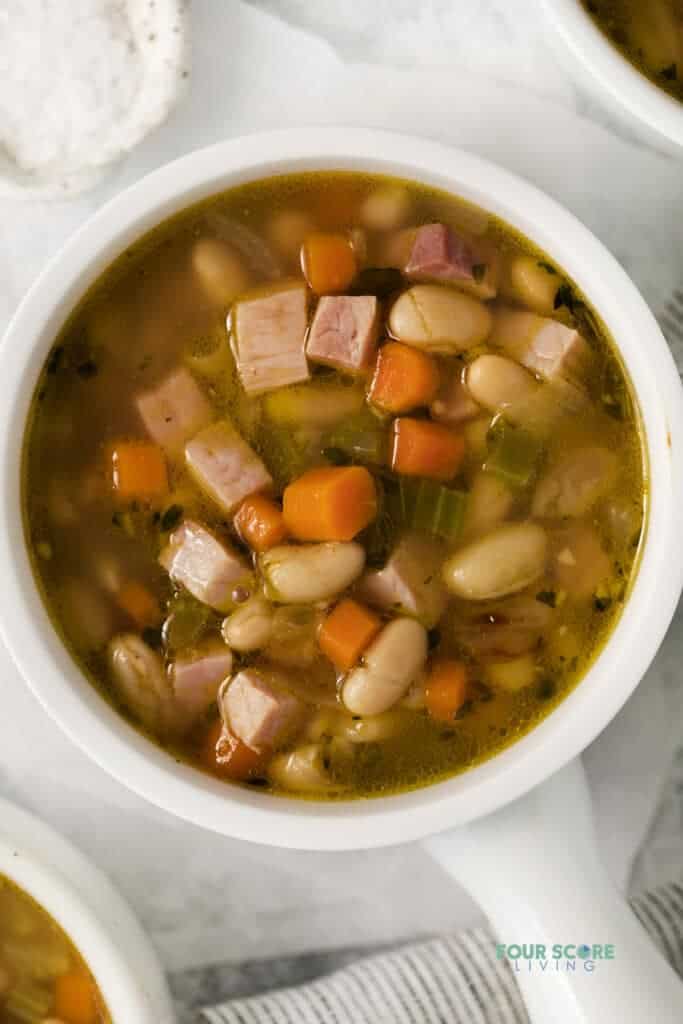 Top view photo of a white bowl filled with Ham and White Bean Soup.