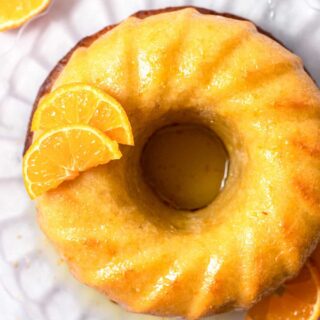 Top view photo of Italian Hangover Cake on a glass serving platter with orange slices placed around the cake in the decorative manner.