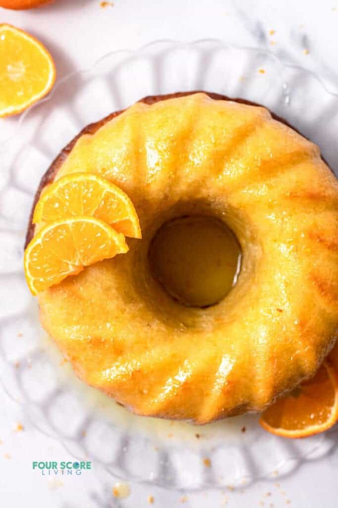 Top view photo of Italian Hangover Cake on a glass serving platter with orange slices placed around the cake in the decorative manner. 