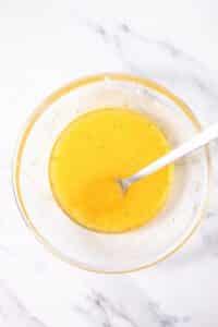 Top view photo of a clear bowl with orange juice, rum, zest, and sugar mixed together to make the glaze for Italian Hangover Cake.