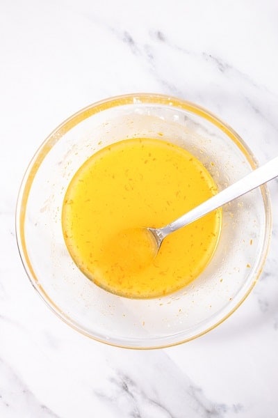 Top view photo of a clear bowl with orange juice, rum, zest, and sugar mixed together to make the glaze for Italian Hangover Cake.