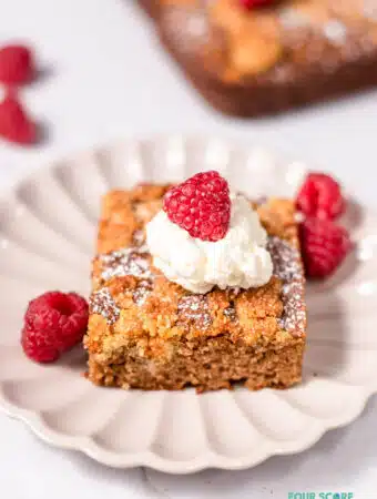 close up of a slice of keto coffee cake topped with whipped cream and a raspberry