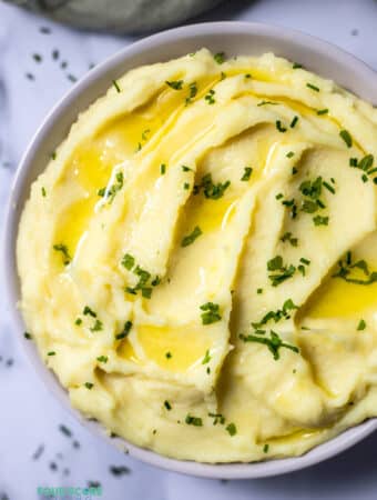 Top view photo of Whipped Potatoes in a bowl with melted butter and chives on top.