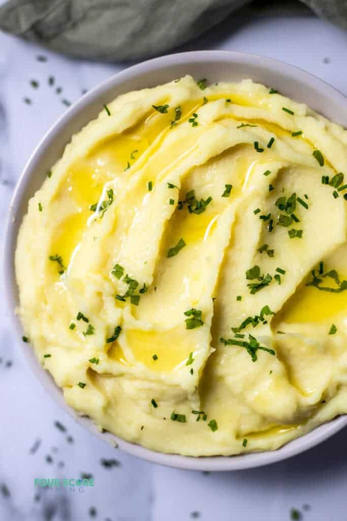 Top view photo of Whipped Potatoes in a bowl with melted butter and chives on top.