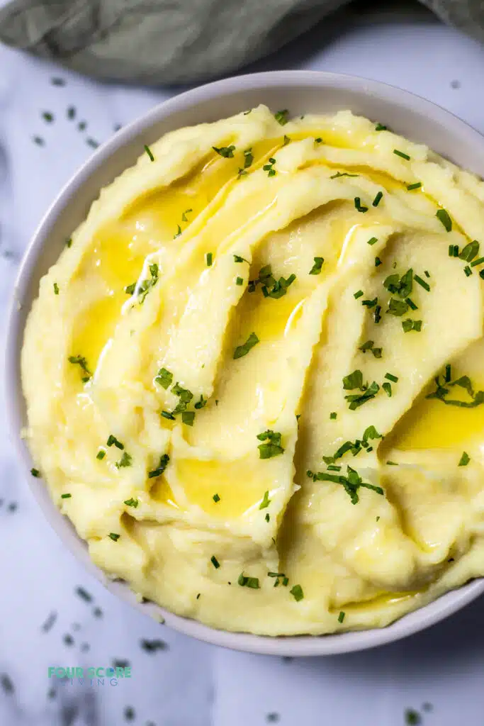 Top view photo of Whipped Potatoes in a bowl with melted butter and chives on top.