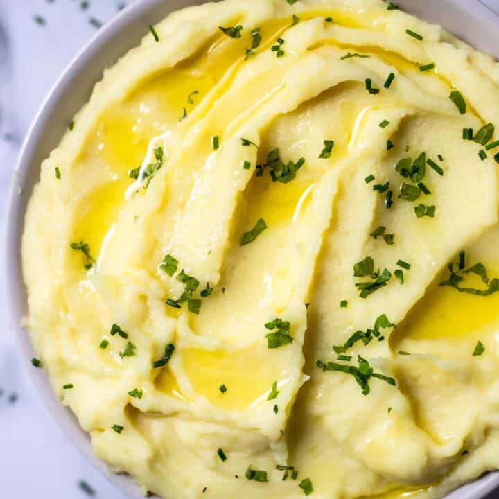 Top view photo of Whipped Potatoes in a bowl with melted butter and chives on top.