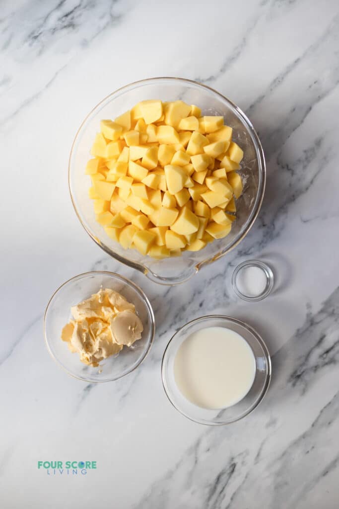 Top view photo of the ingredients to make Whipped Potatoes in separate bowls.