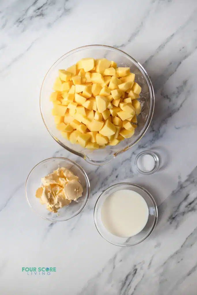 Top view photo of the ingredients to make Whipped Potatoes in separate bowls.