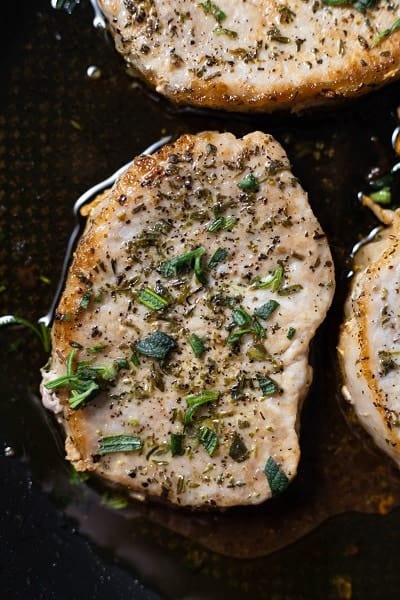 Closeup photo of a pork chop, seared until golden brown.