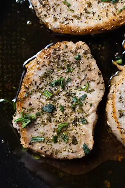 Closeup photo of a pork chop, seared until golden brown.