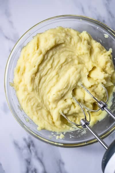 Top view photo of potatoes in a clear bowl, whipped until fluffy.