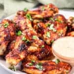 side view of keto chicken wings on a white plate with sauce
