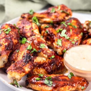 side view of keto chicken wings on a white plate with sauce