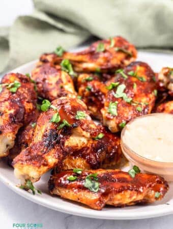 side view of keto chicken wings on a white plate with sauce