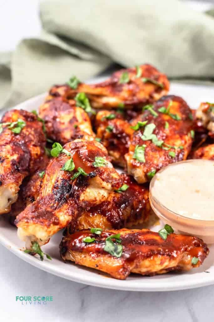 side view of keto chicken wings on a white plate with sauce