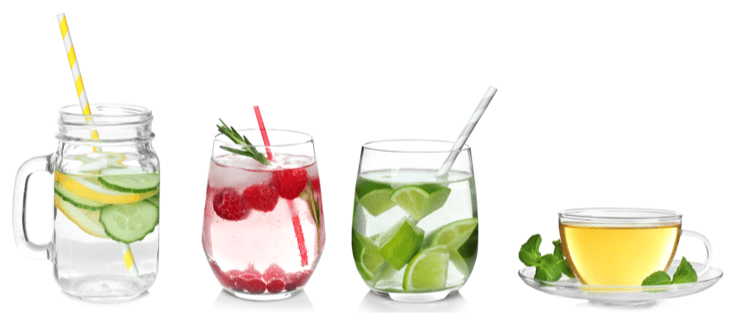 Keto infused water. A glass jar with a handle containing sliced lemons and cucumbers and a straw, a small glass containing ice, raspberries, a spring of fresh rosemary, a small glass with cubed pieces of fresh lime and a paper straw, a clear glass teacup and saucer, the cup is filled with light colored tea and there are fresh mint leaves on the saucer