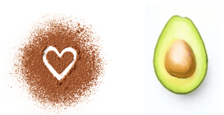 cocoa powder sprinkled on a white surface with a heart drawn into it, a half of a full avocado placed on a surface with skin side down and seed side up.