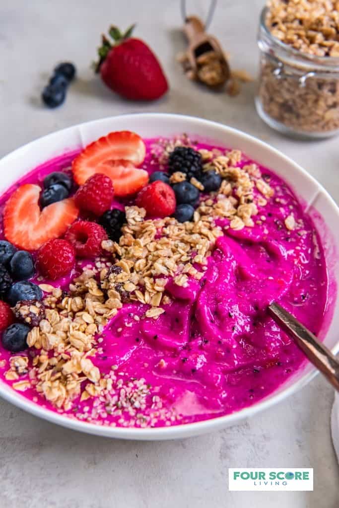 dragon fruit smoothie bowl with strawberries, blueberries, blackberries and granola layered on top