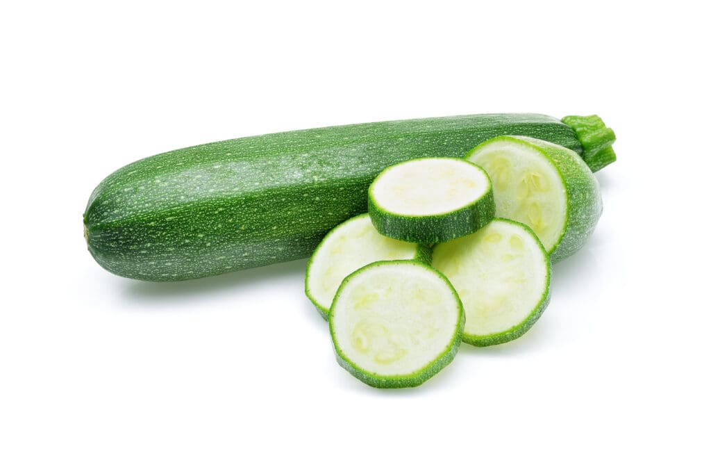 One whole zucchini and a part of a zucchini and 4 zucchini slices isolated on white background.