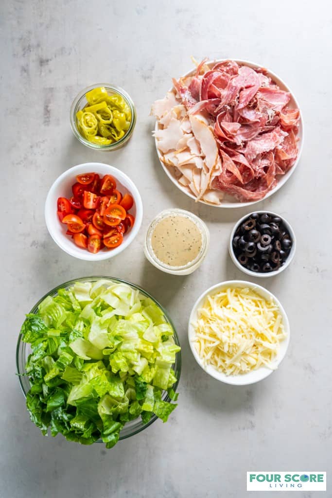 Top view photo of all the ingredients to make Grinder Salad, in separate bowls.