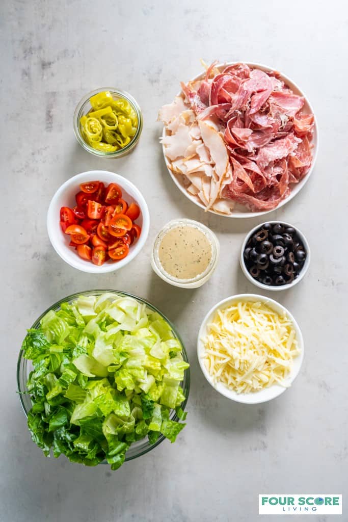 Top view photo of all the ingredients to make Grinder Salad, in separate bowls. 