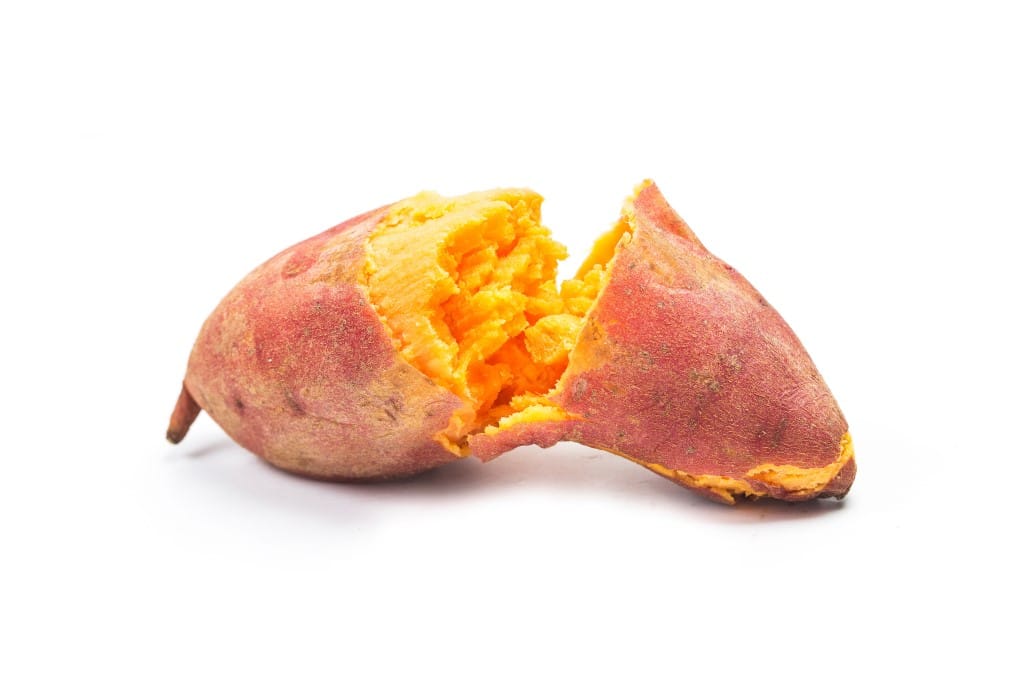 Baked sweet potato split open to reveal flesh on white background.