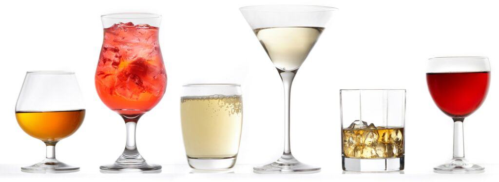 Keto approved alcohol drinks. Four stemware glasses and two small glasses filled with colored liquid that appears to be wine and spirits. One small glass also contains ice.