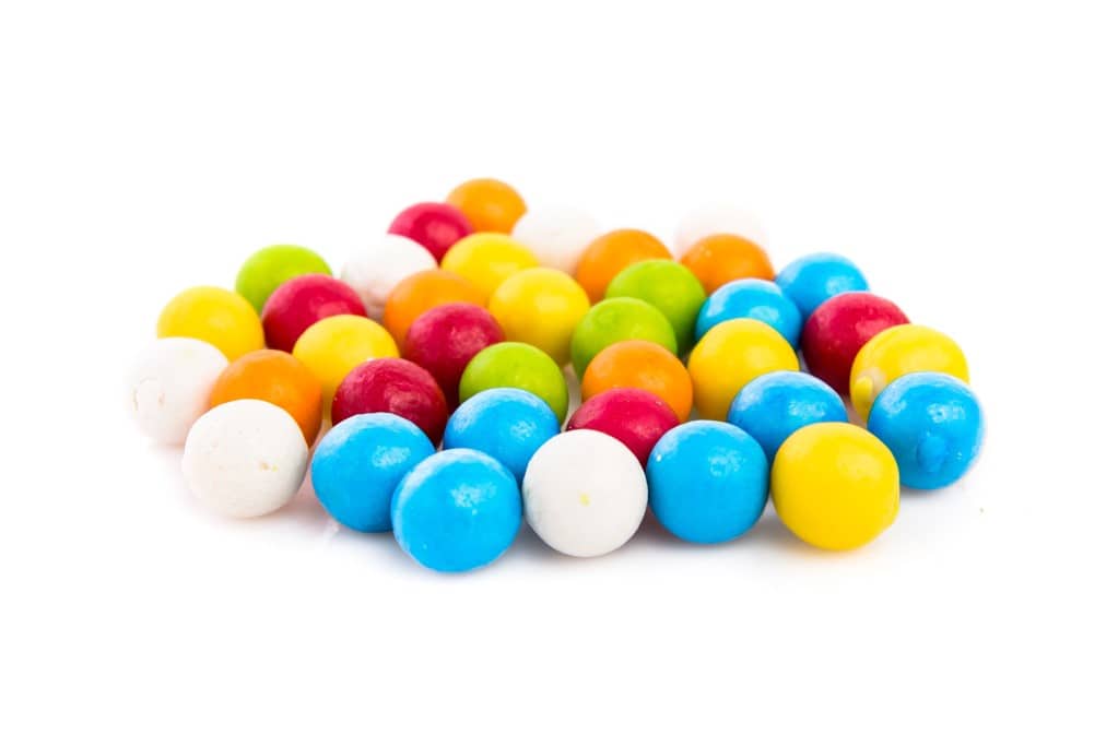 Approximately 30 colorful small gumballs clustered together on a white background.