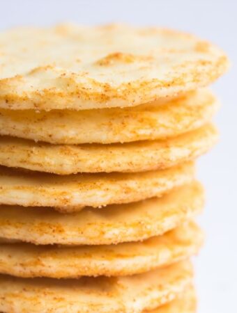 A closeup aerial view of a stack of salted and orange spiced rice crackers on an empty background.