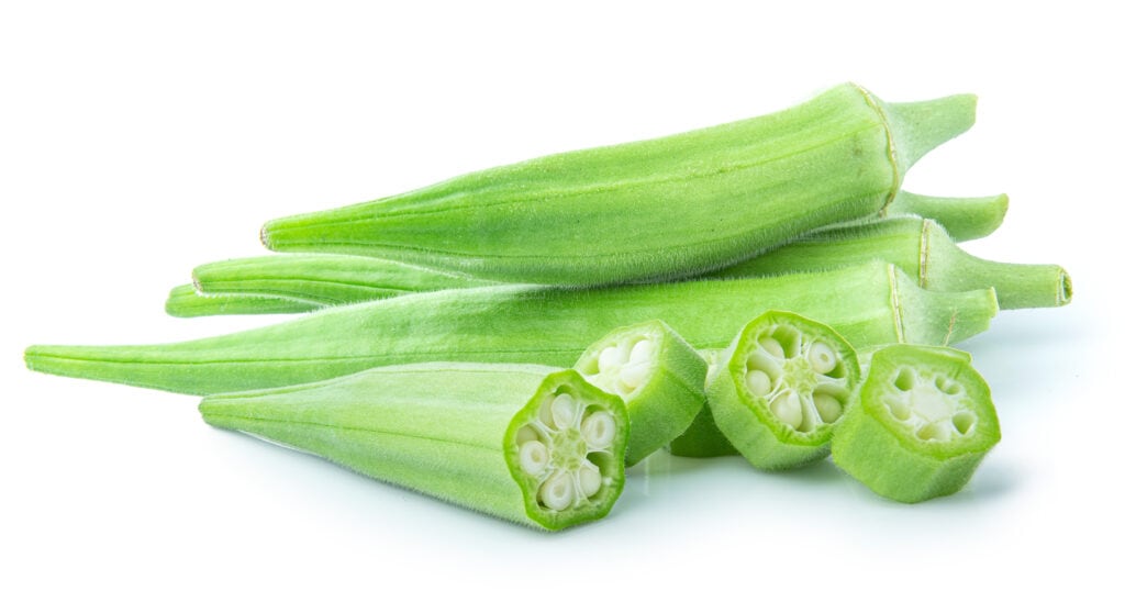 Frontal view of five okra, four whole and one sliced isolated on a white background. 