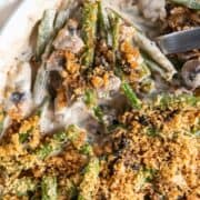 A spoonful of keto green bean casserole being scooped out of a casserole dish.